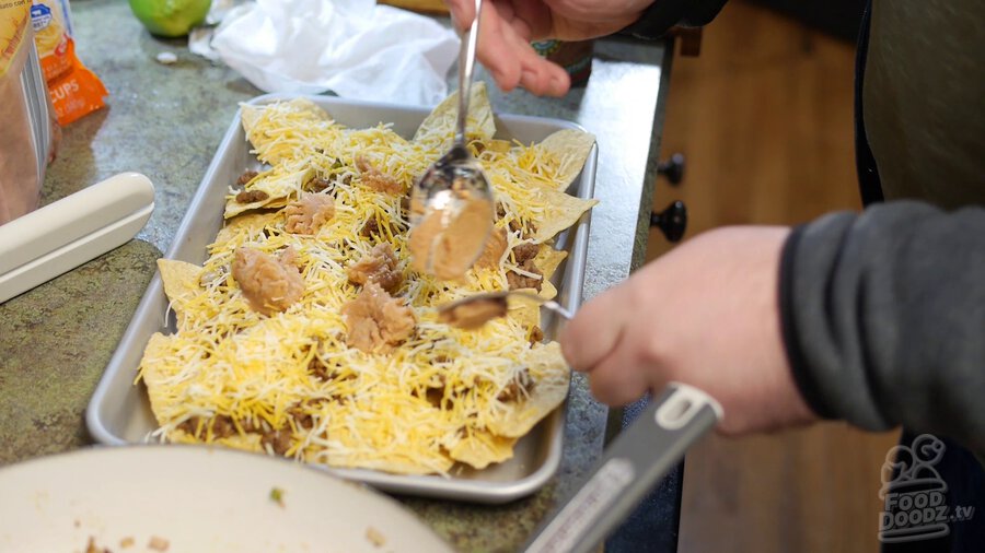 Refried beans are spooned on top of previous layer of cheese