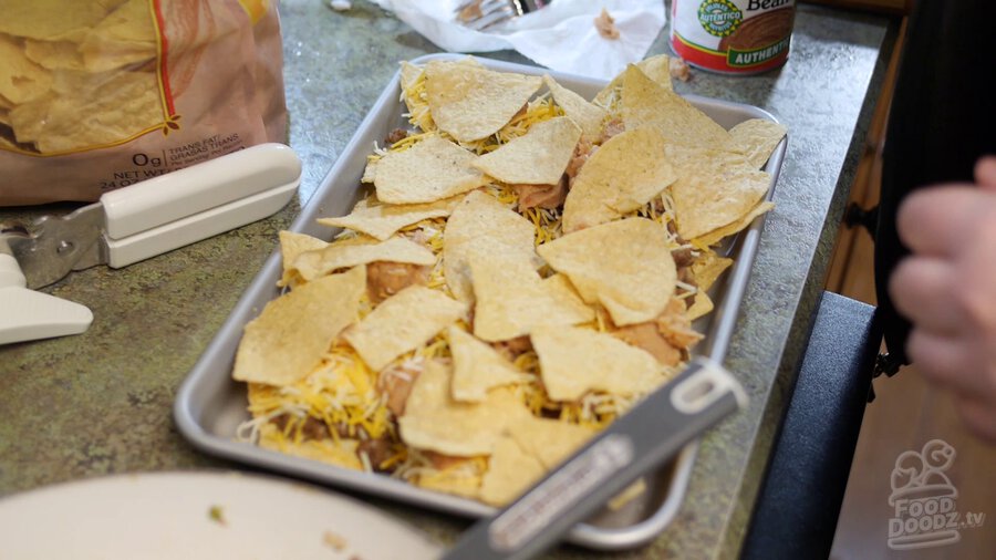 Another layer of tortilla chips is added on top of the refried beens