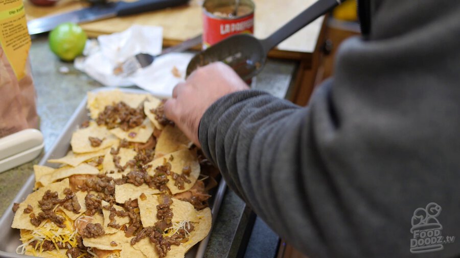 Ground beef is spooned on top of the layer of tortilla chips