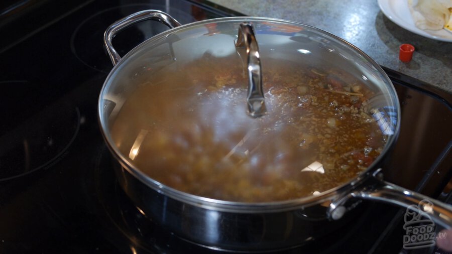 A lid is placed on pan and steam can be seen forming inside vessel