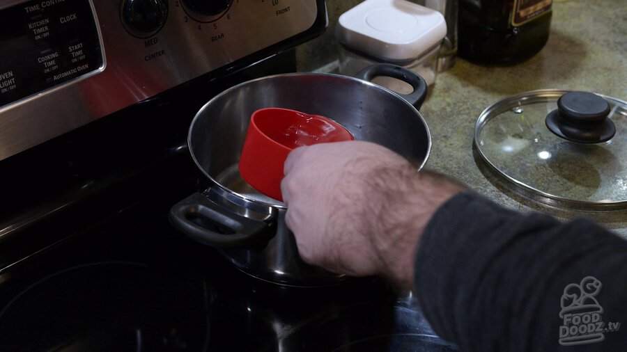 Water is added to sauce pan using measuring cup