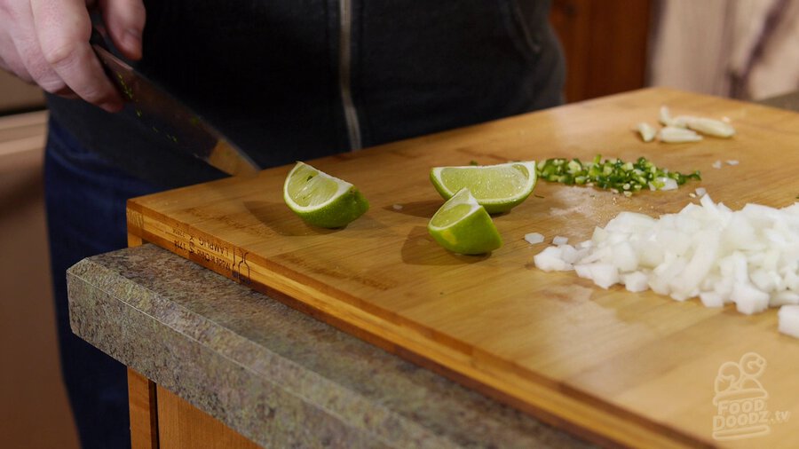 Limes are cut into slices on wooden cutting board