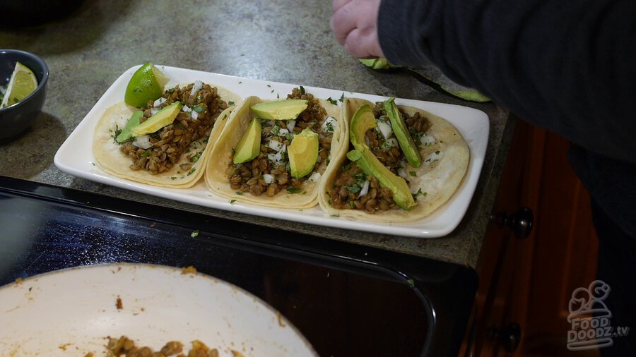 Delicious plate of lentil tacos is assembled with slices of avacado and chopped cilantro on top. Yum!