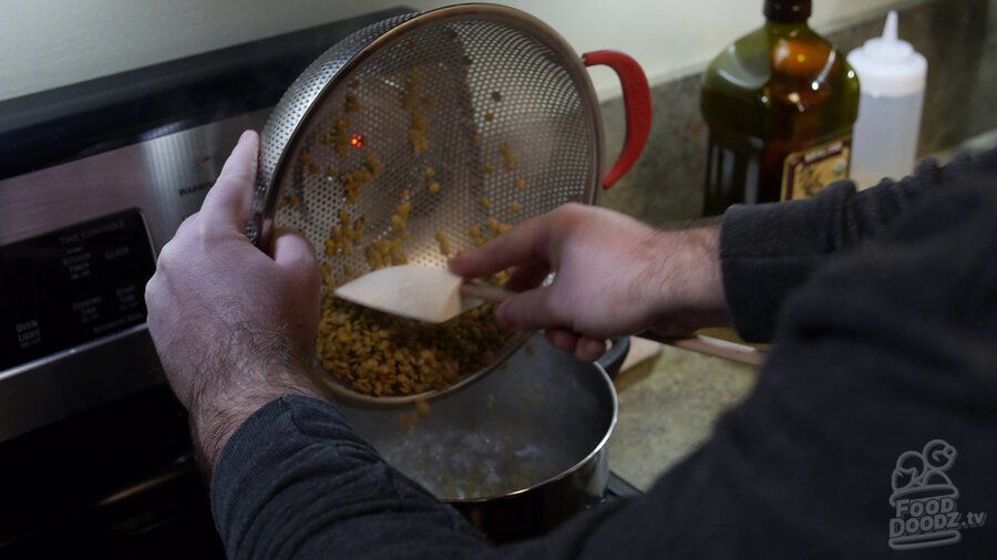 Lentils are scraped out of colander with spoon and into pot of boiling water