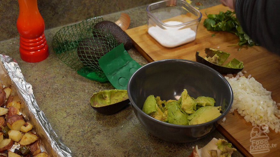 Avocado is removed from casing and added to bowl.