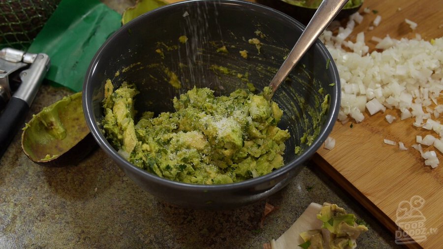 Salt is sprinkled into bowl of guacamole
