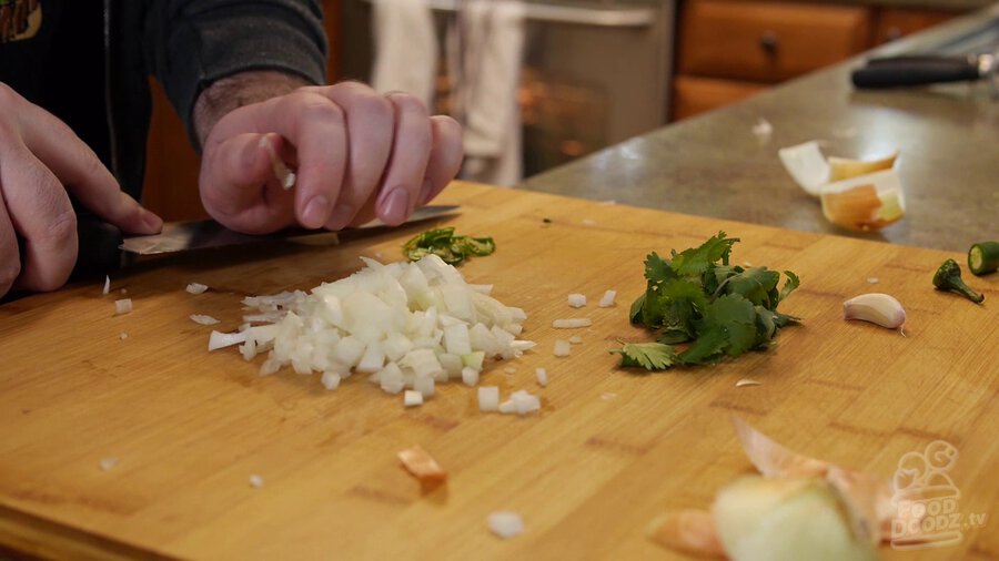 Using side of chef's knife and bottom of hand to pound down garlic and release it from its wrapper