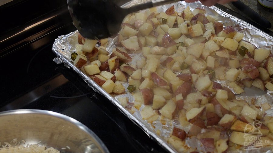 Steaming hot potato mixture is removed from oven and sits on top of oven. A spatula is used to scrape parts that have stuck and flip everything to help get everything to brown evenly on both sides.