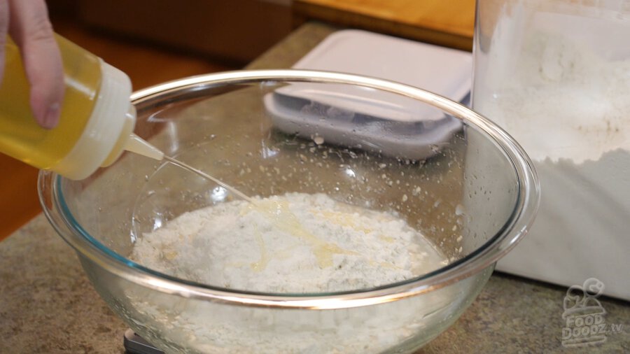 Adding vegetable oil with squirt bottle to large mixing glass bowl