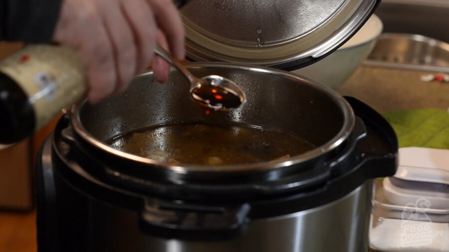 Using spoon to carefully added fish sauce out of bottle to Vietnamese Pho broth in Instant Pot