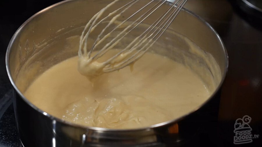 Showing how cashew mixture thickens and starts to clump together on end of whisk