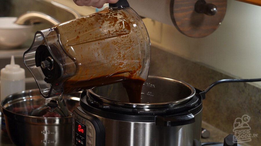 Hand pours pureed chili mixture back into Instant Pot