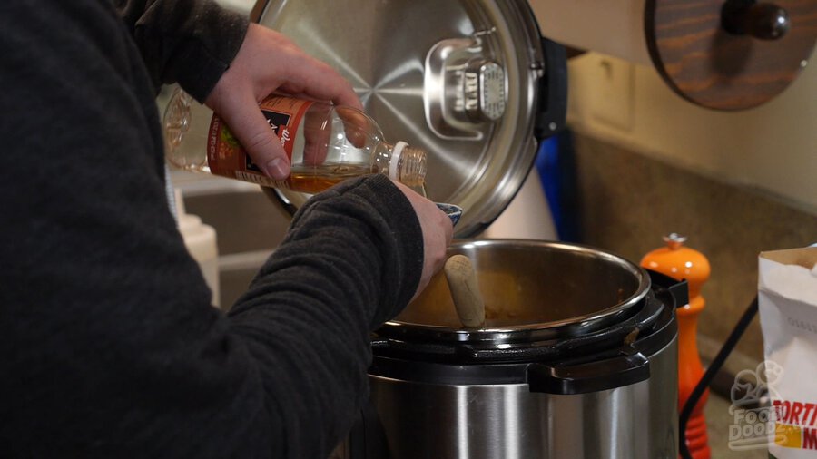 Man measures apple cider vinegar into measuring cup over Instant Pot