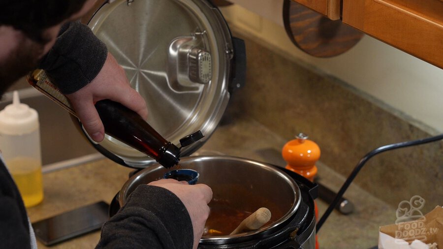 Man measures fish sauce from bottle into measuring cup over Instant Pot