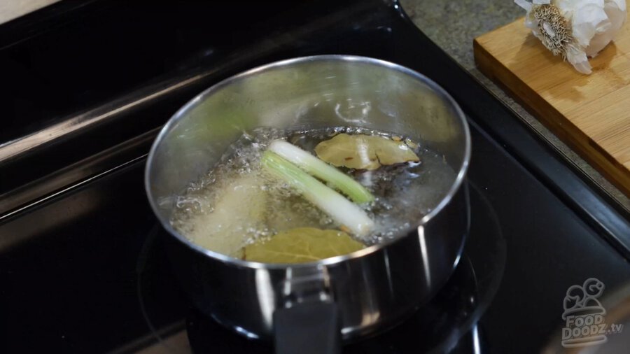 A pot of simmering oil with spices and aromatics