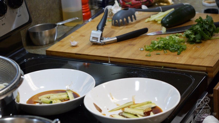 2 bowls with sesame paste, soy sauce, sugar, chinkiang vinegar, and cucumbers