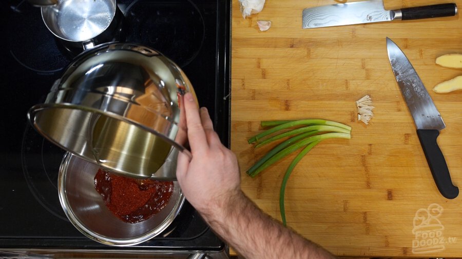 Pouring hot oil over chili flakes