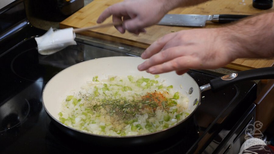 garlic powder, onion powder, thyme, cayenne, salt, pepper and rosemary added to onions and peppers in a pan