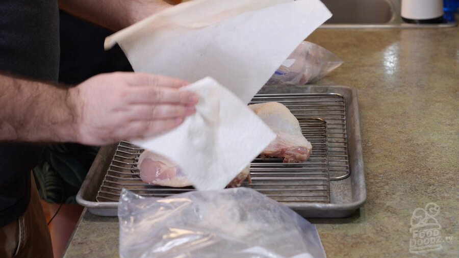 Patting down raw chicken with paper towels