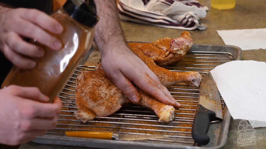 Barbecue seasoning being rubbed into chicken quarters 