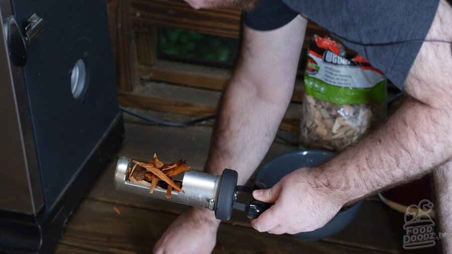 Soaked applewood chips being loaded into smoker firebox