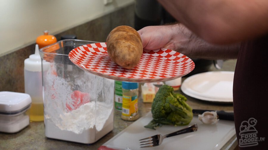 Putting potato on plate in microwave