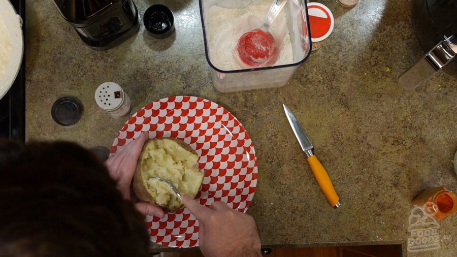 Split open baked potato being mashed with a fork