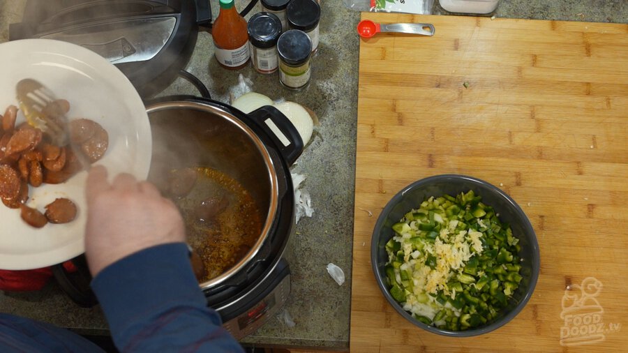 Taking browned andouille out of the pot