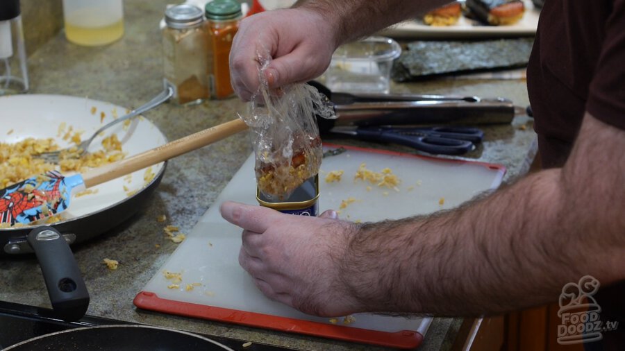 Plastic Wrapped musubi being removed from the can