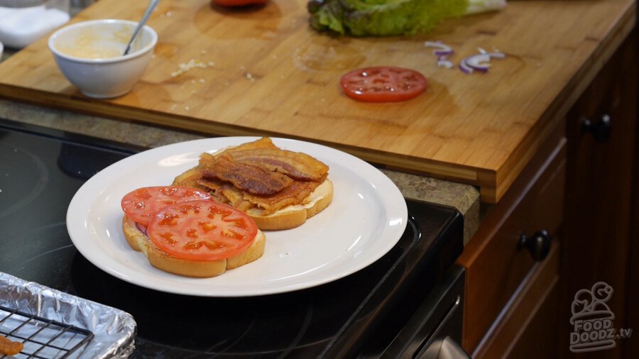 Adding tomato to mayoed bread