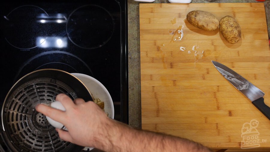 Spraying air fryer basket with cooking spray