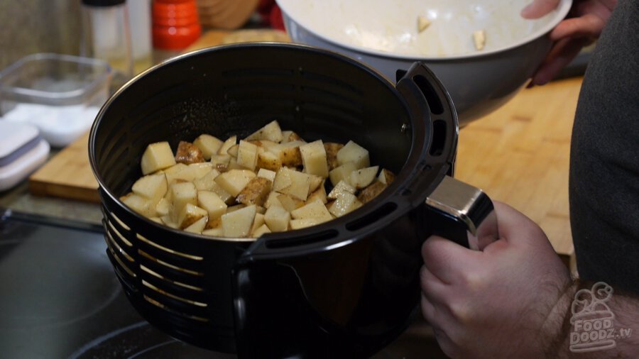 Raw seasoned potatoes in air fryer basket