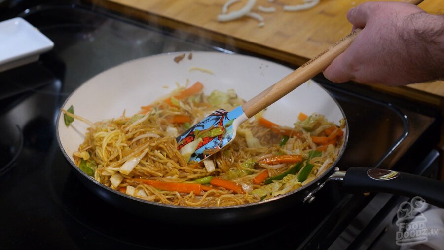 Throughly mixing the sauce all around the noodles