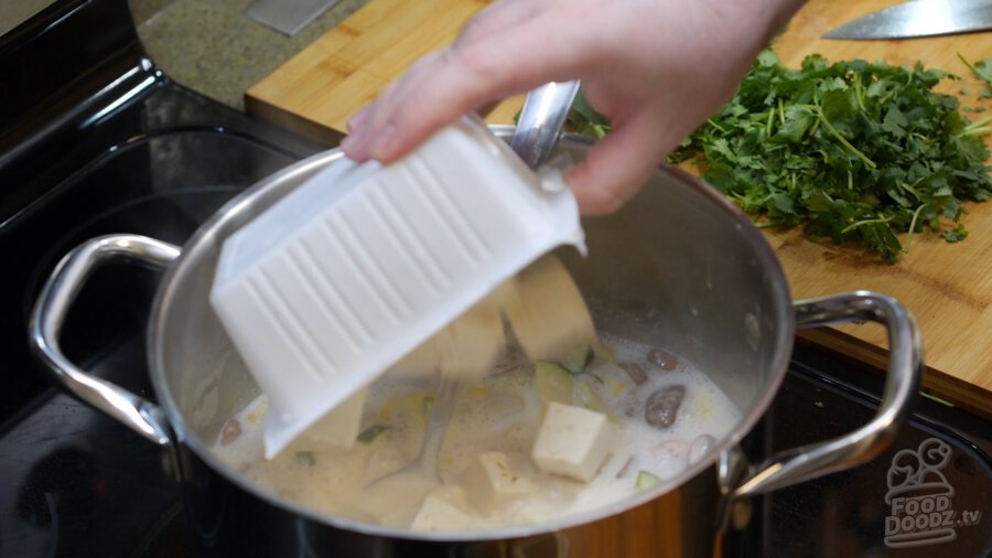 Chopped tofu being added to pot