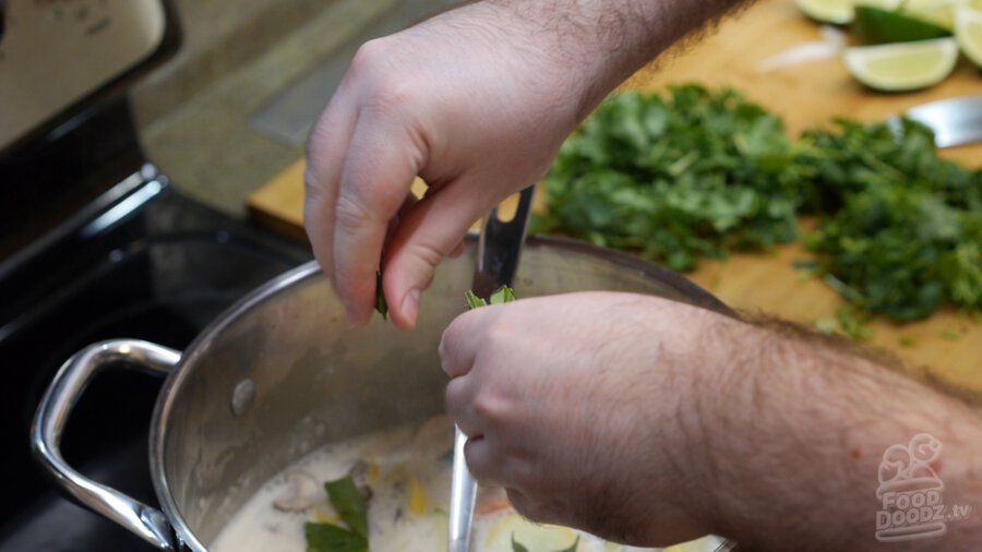 Kaffir lime leaves being added to the pot