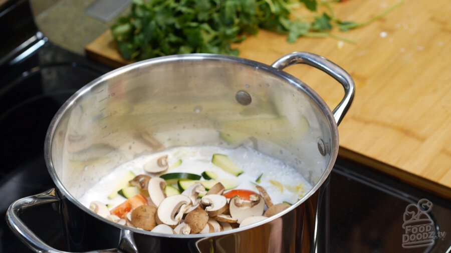 Coconut milk, lemongrass, ginger, onion, tomatoes, mushrooms, yellow squash, zucchini, and the thai chiles added to a large stock pot