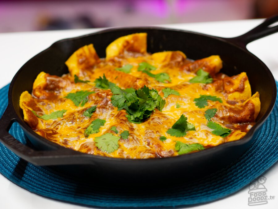 A cast iron skillet full of tex mex cheese and onion enchilada goodness.