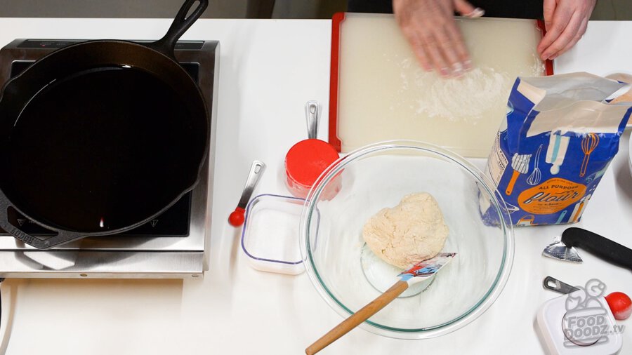 Lightly adding flour to cutting board for making fry bread on