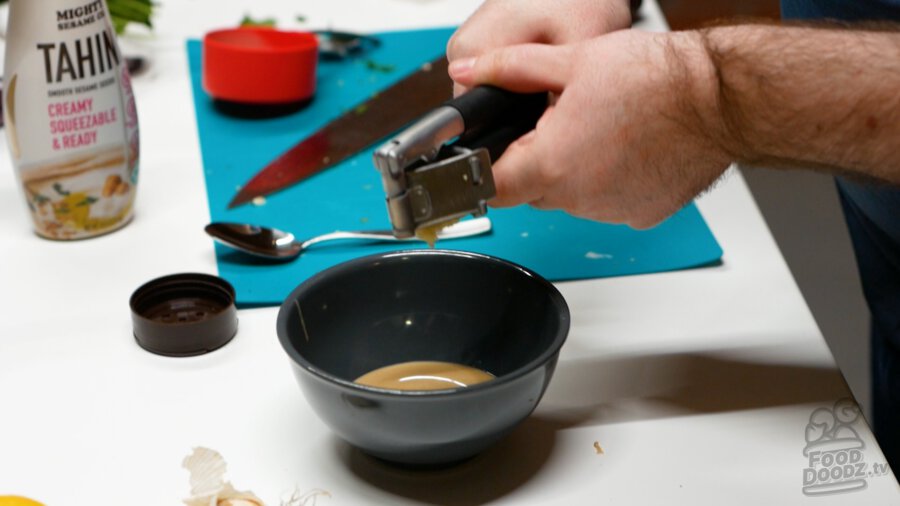 Adding garlic through a garlic press to the bowl