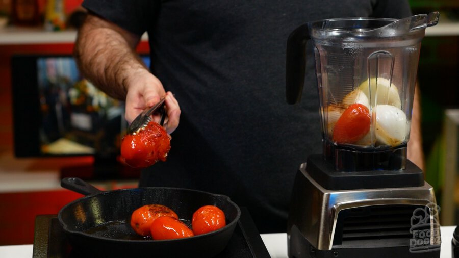 A well charred tomato being removed to a blender