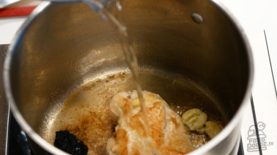 Adding the water to the chicken, garlic, and dried chiles.