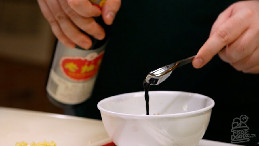 Adding dark soy sauce to bowl