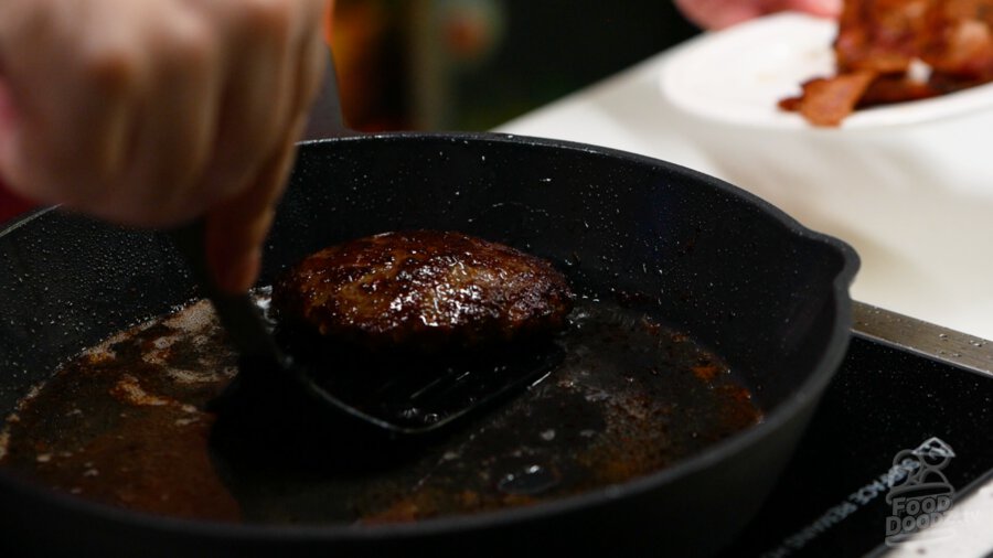 Removing the cooked sausage patty from the pan