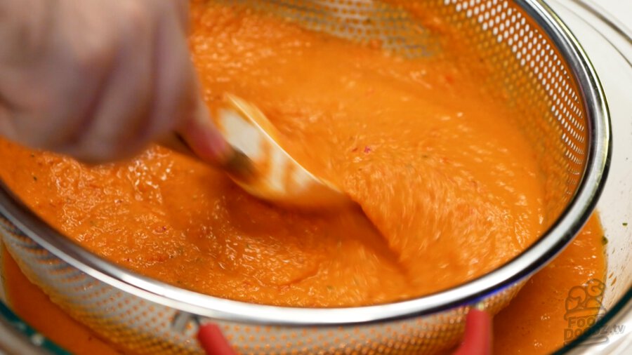 Stiring the gazpacho through the colander to remove tomato and pepper skins