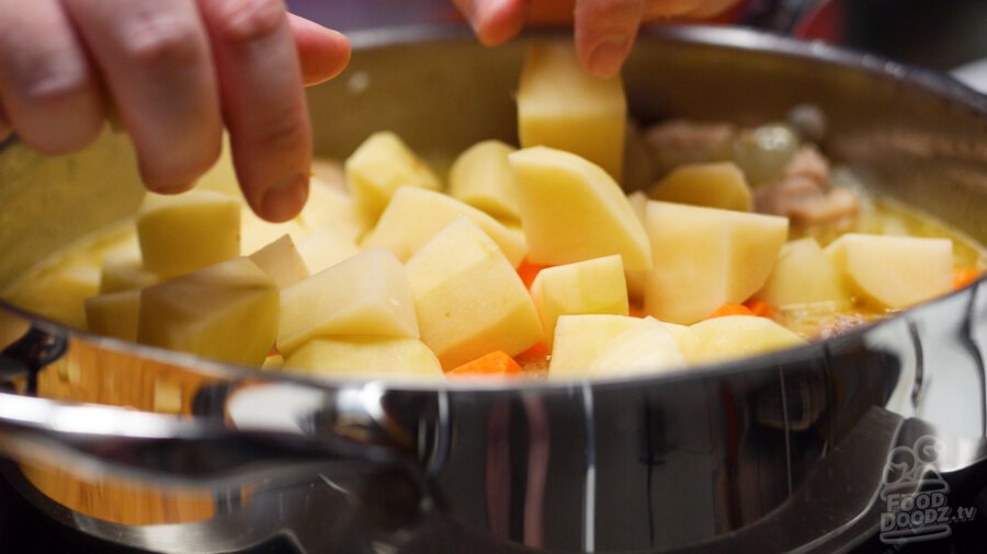 adding carrots and potatoes to pan