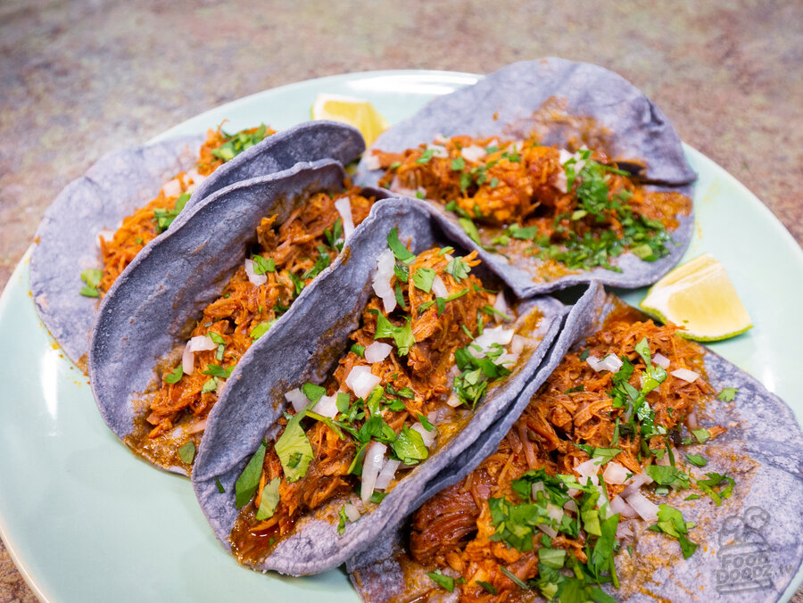 Delicous carnitas served in corn tortillas that are topped with onion, cilantro, and lime juice