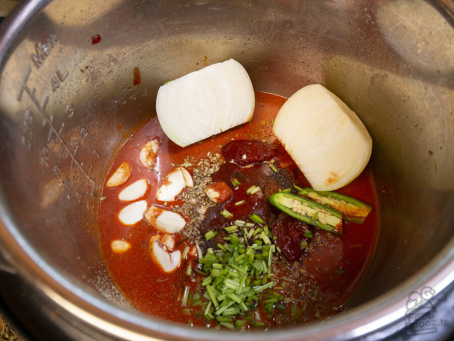 water, garlic powder, onion powder, oregano, salt, cumin, cloves, chili powder, garlic cloves, onion, serrano, and chipotles added to pan